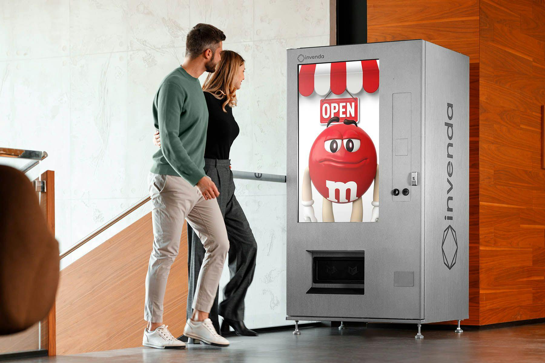 Woman and man looking at full screen ad on smart vending machine