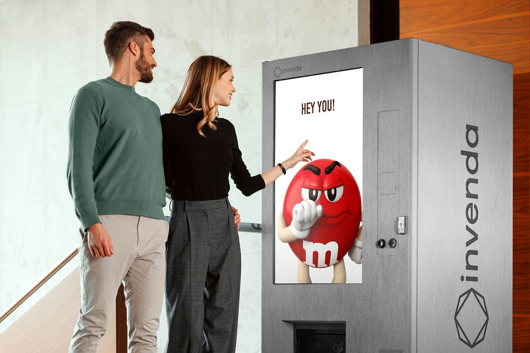 Man and woman looking at full screen ad on smart vending machine